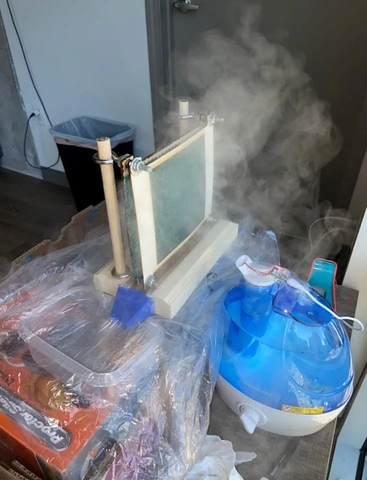 The full test setup: the humidifier blowing a column of fog up through the mesh frame, with the collection box wrapped in plastic beside it.